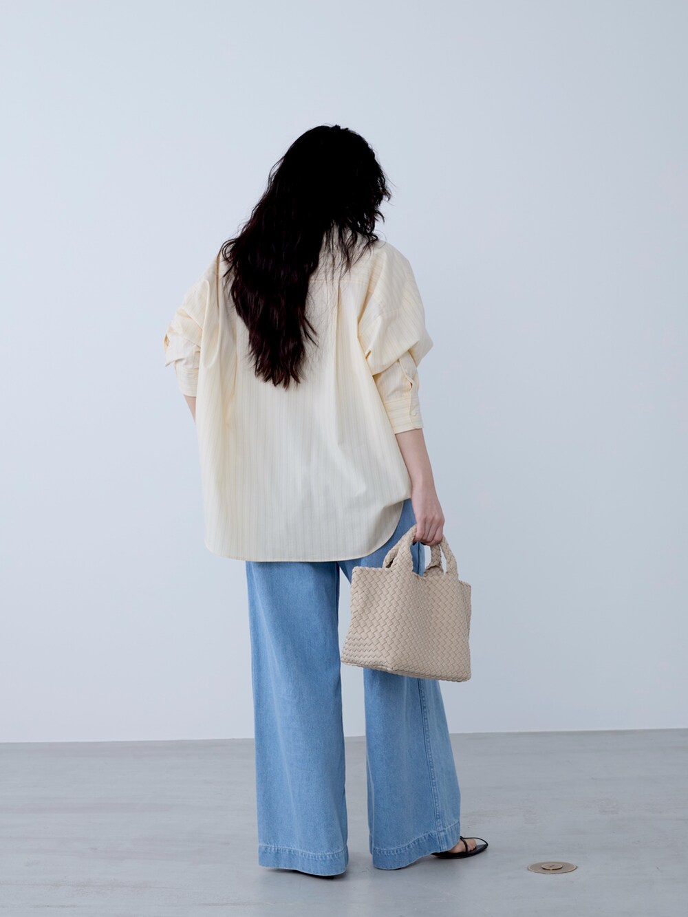 イエロー系のシャツ/ブラウス、ベージュ系のトートバッグ、ブルー系のチノパンツを着用したレディースの冬コーディネートの5枚目の写真