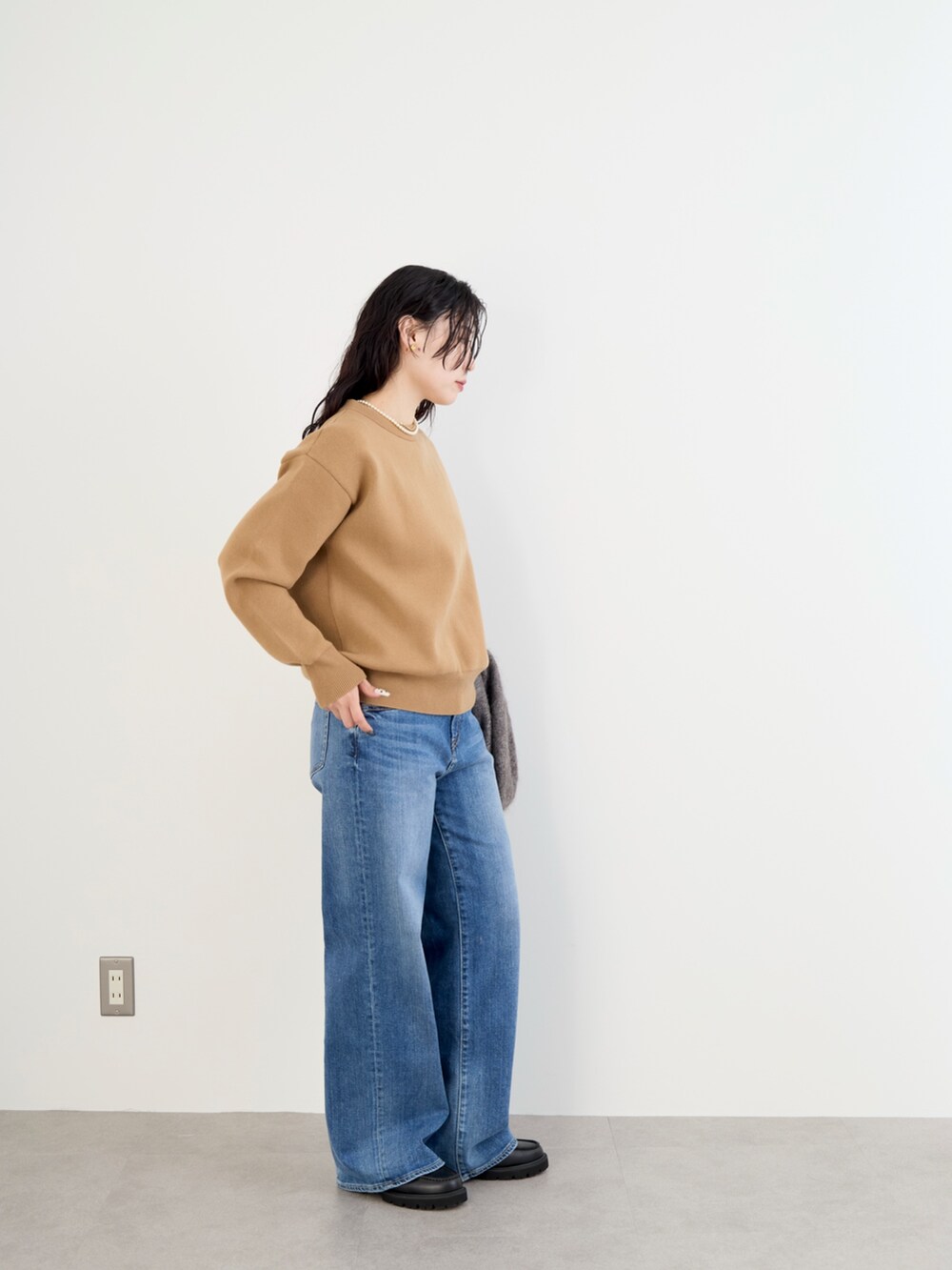 ベージュ系のステンカラーコート、イエロー系のニット/セーター、ブルー系のデニムパンツを着用したレディースの冬コーディネートの8枚目の写真