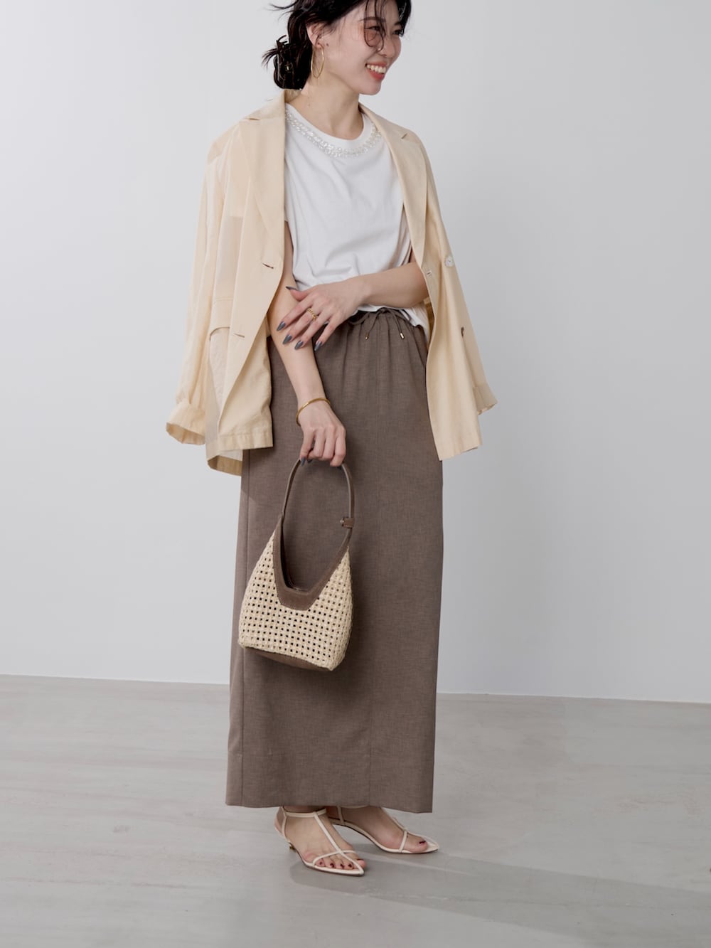 ホワイト系のTシャツ/カットソー、ブラウン系のハンドバッグ、ベージュ系のテーラードジャケットを着用したレディースの春コーディネートの2枚目の写真