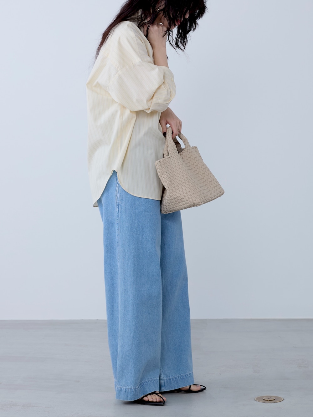 イエロー系のシャツ/ブラウス、ベージュ系のトートバッグ、ブルー系のチノパンツを着用したレディースの冬コーディネートの4枚目の写真