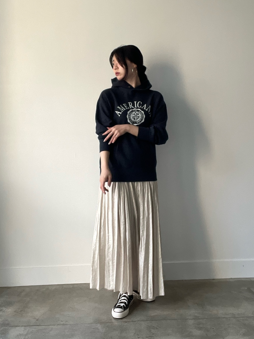 ブラック系のパーカー、ベージュ系のスカートを着用したレディースの秋コーディネートの2枚目の写真