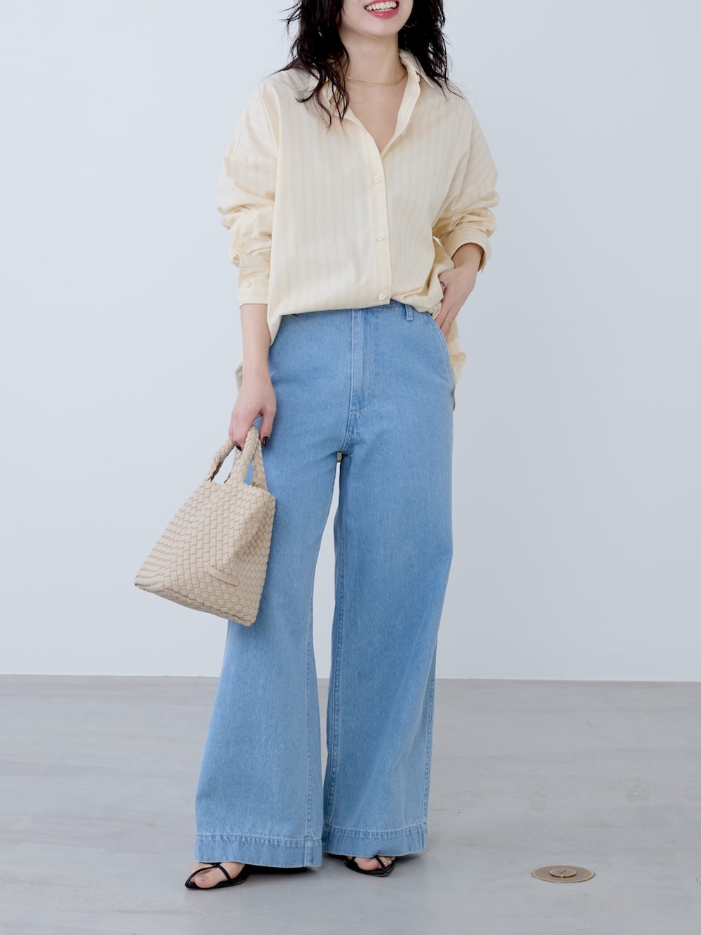 イエロー系のシャツ/ブラウス、ベージュ系のトートバッグ、ブルー系のチノパンツを着用したレディースの冬コーディネートの2枚目の写真