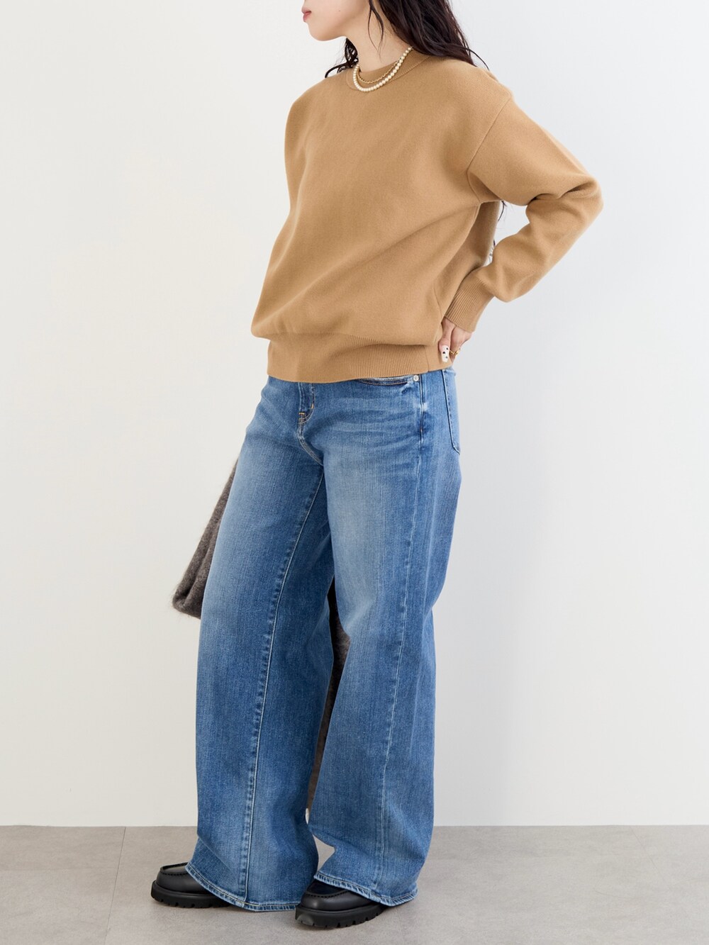 ベージュ系のステンカラーコート、イエロー系のニット/セーター、ブルー系のデニムパンツを着用したレディースの冬コーディネートの7枚目の写真