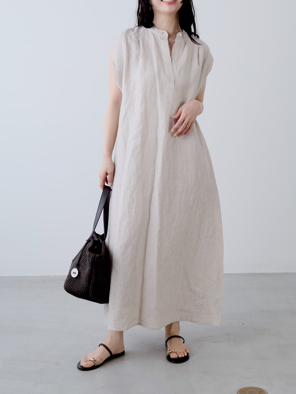 ベージュ系のワンピース、ブラウン系のトートバッグ、ブラウン系のサンダルを着用したレディースの夏コーディネートの4枚目の写真