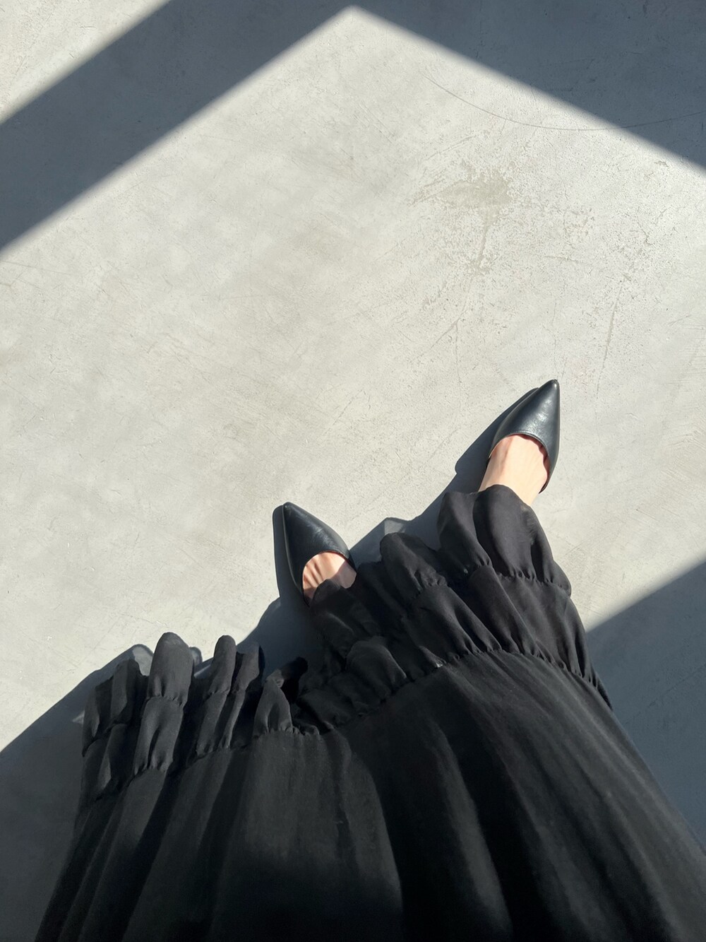 ブラック系のスカート、シルバー系のタンクトップ、ブラック系のカーディガン/ボレロを着用したレディースの春コーディネートの5枚目の写真