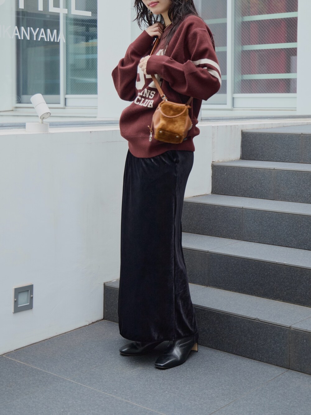 ブラック系のスカート、イエロー系のハンドバッグ、ブラウン系のニット/セーターを着用したレディースの秋コーディネートの2枚目の写真