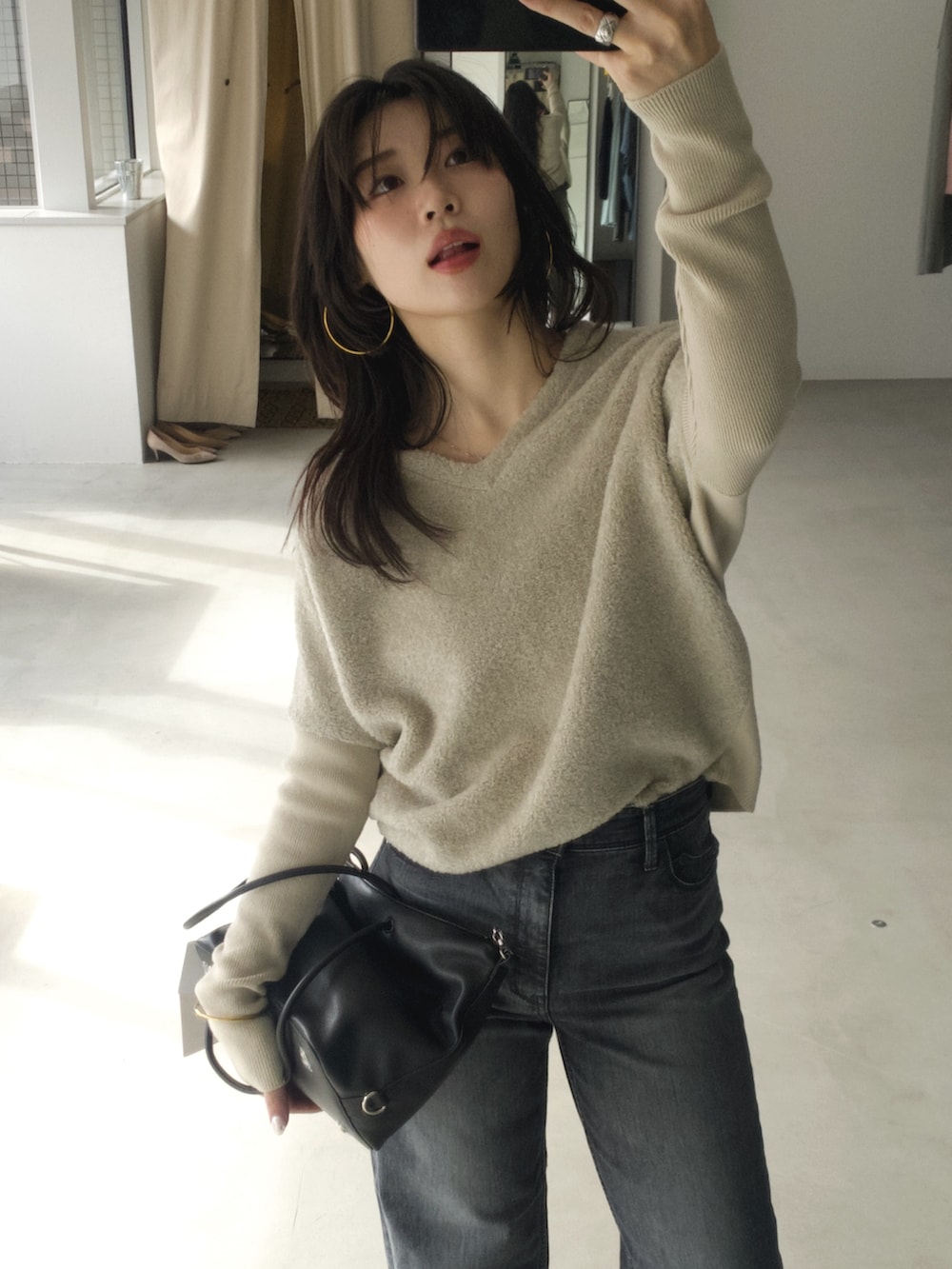 グレー系のニット/セーター、ブラック系のボストンバッグ、グレー系のデニムパンツを着用したレディースの冬コーディネートの2枚目の写真