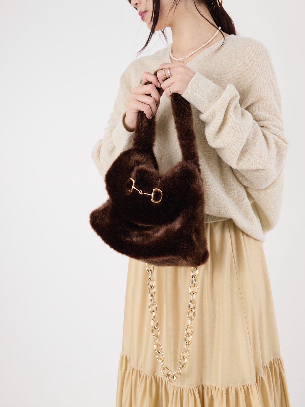 ホワイト系のニット/セーター、ベージュ系のスカート、ブラウン系のハンドバッグを着用したレディースの冬コーディネートの4枚目の写真