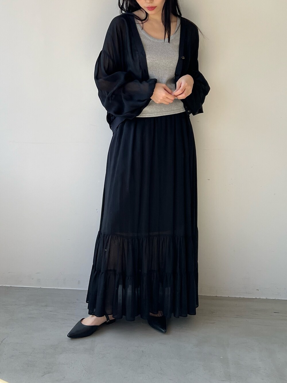 ブラック系のスカート、シルバー系のタンクトップ、ブラック系のカーディガン/ボレロを着用したレディースの春コーディネートの2枚目の写真