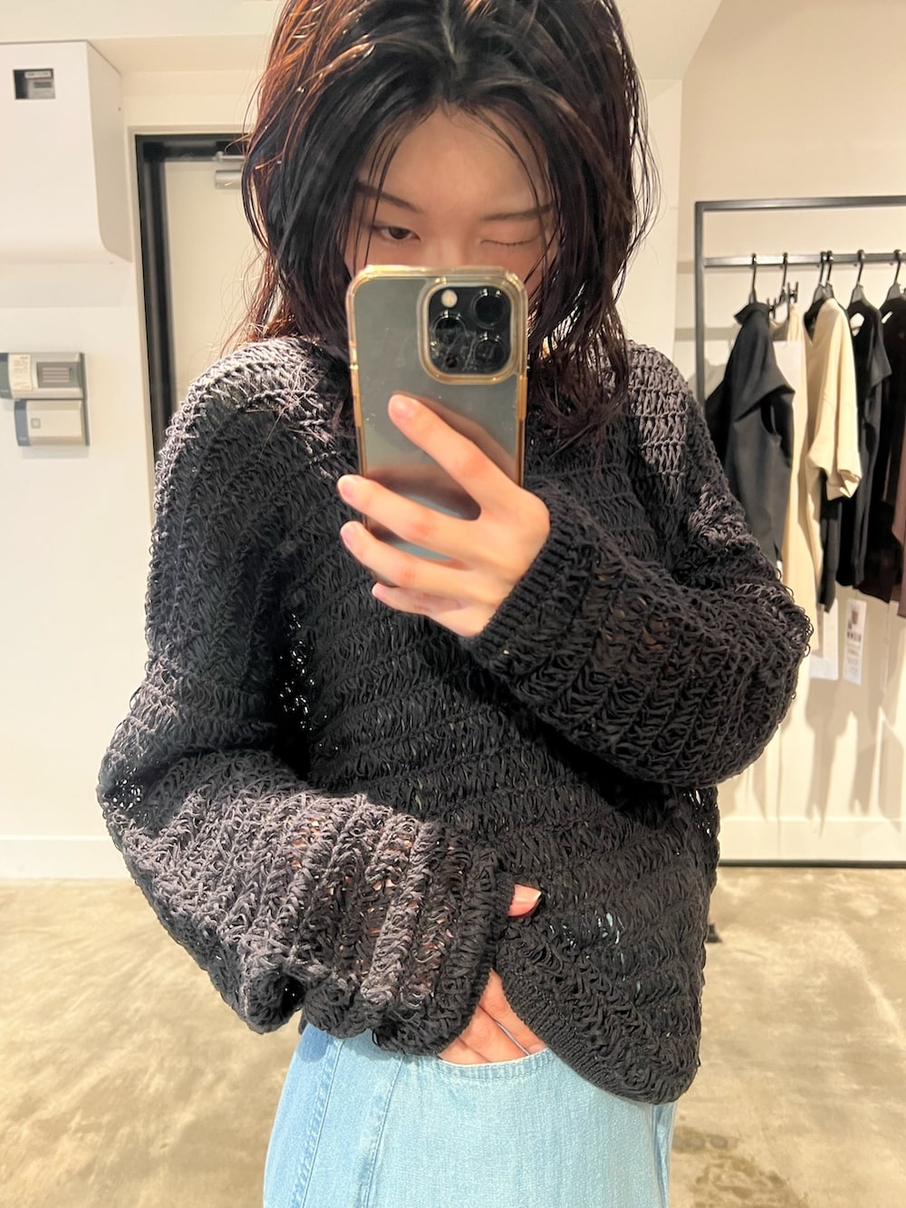 ブラック系のニット/セーター、ブルー系のスカートを着用したレディースの春コーディネートの3枚目の写真