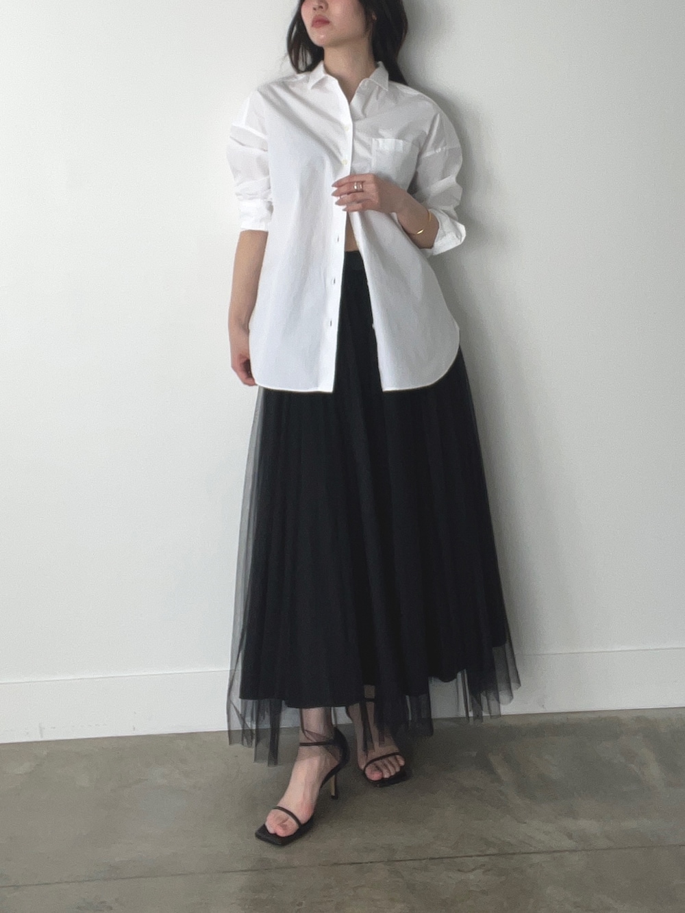 ブラック系のスカート、ホワイト系のシャツ/ブラウスを着用したレディースの春コーディネートの2枚目の写真