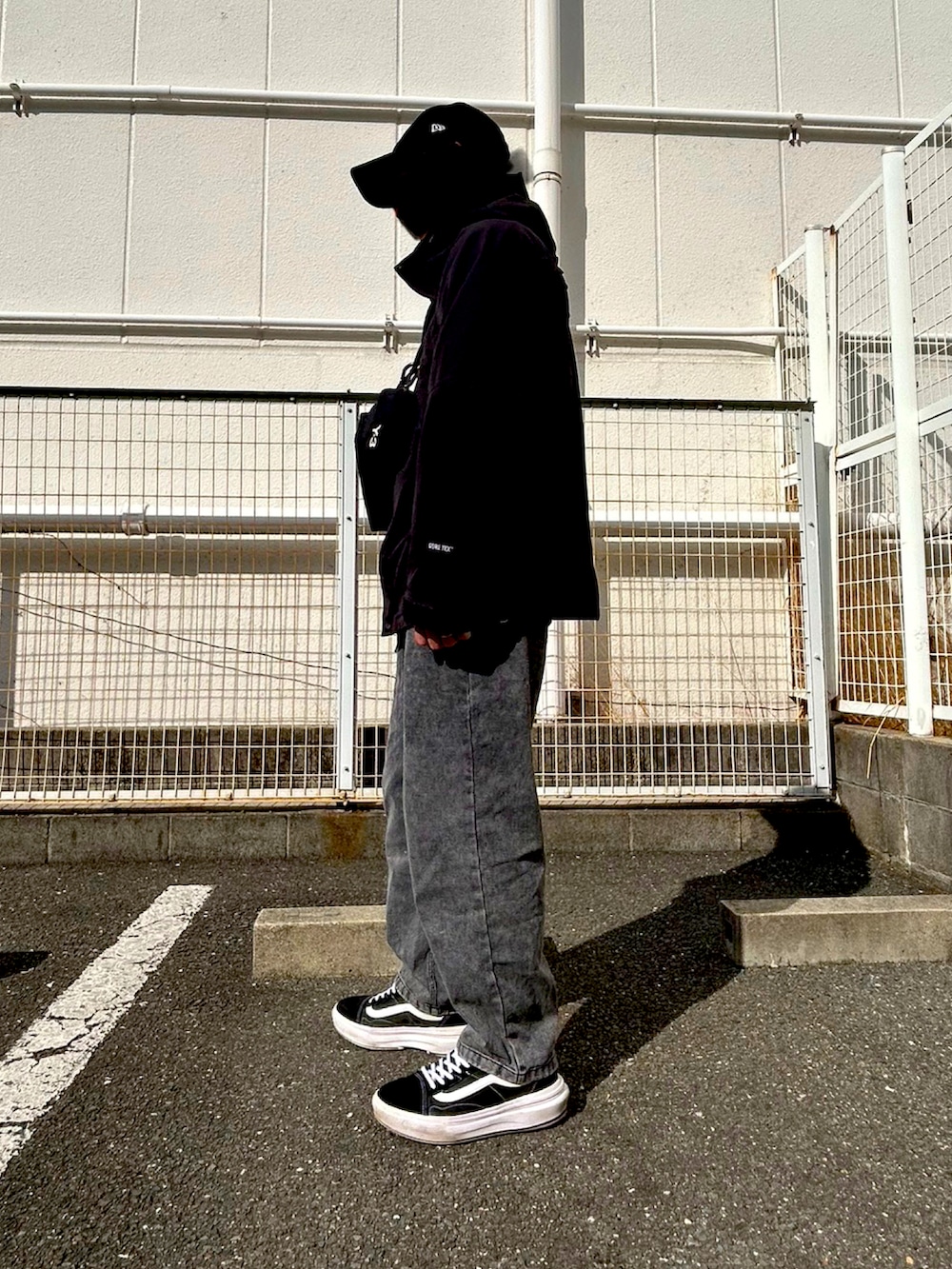 ブラック系のボディバッグ/ウエストポーチ、ブラック系のメッセンジャーバッグ、ブラック系のマウンテンパーカーを着用したメンズの冬コーディネートの2枚目の写真