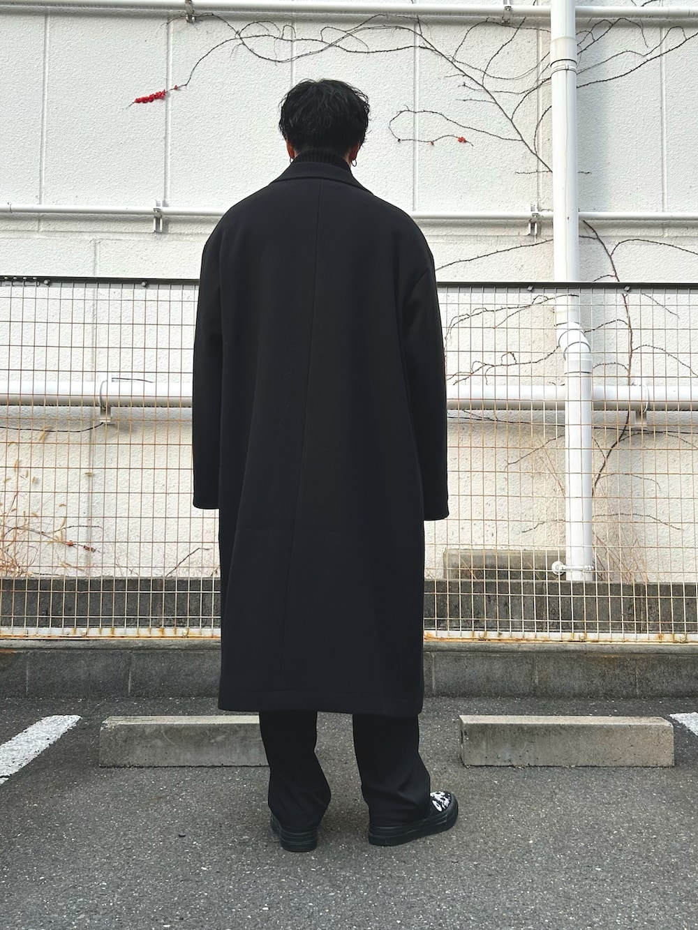 ブラック系のチェスターコート、ブラック系のブルゾン、ブラック系のニット/セーターを着用したメンズの冬コーディネートの3枚目の写真