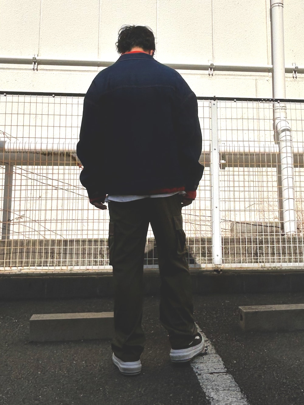 オレンジ系のスウェット、ブラック系のデニムジャケット、グリーン系のカーゴパンツを着用したメンズの冬コーディネートの4枚目の写真