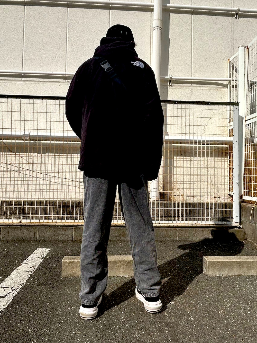 ブラック系のボディバッグ/ウエストポーチ、ブラック系のメッセンジャーバッグ、ブラック系のマウンテンパーカーを着用したメンズの冬コーディネートの3枚目の写真