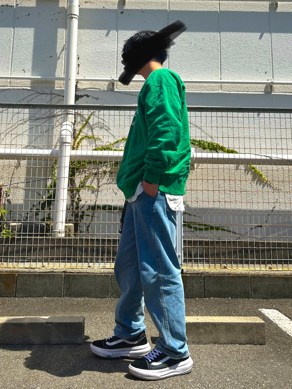 グリーン系のスウェット、ブルー系のデニムパンツ、ブラック系のスニーカーを着用したメンズの夏コーディネートの2枚目の写真