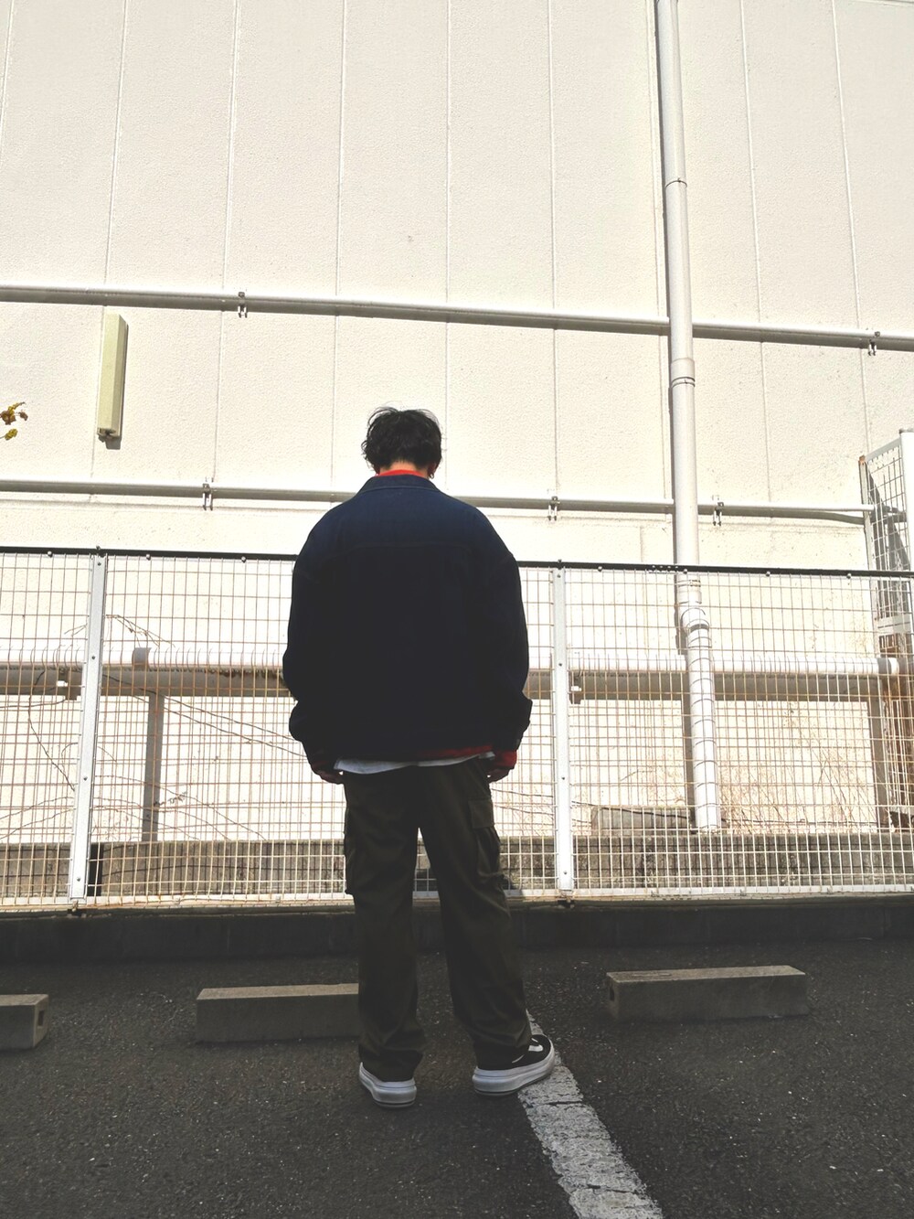 オレンジ系のスウェット、ブラック系のデニムジャケット、グリーン系のカーゴパンツを着用したメンズの冬コーディネートの3枚目の写真