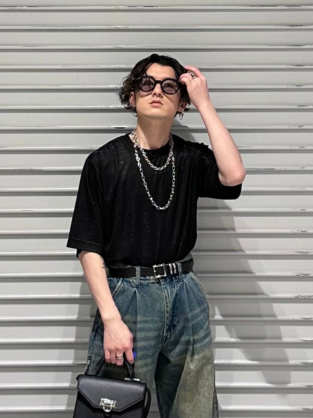 ブラック系のドレスシューズ、ブラック系のショルダーバッグ、ブルー系のデニムパンツを着用したメンズの春コーディネートの2枚目の写真