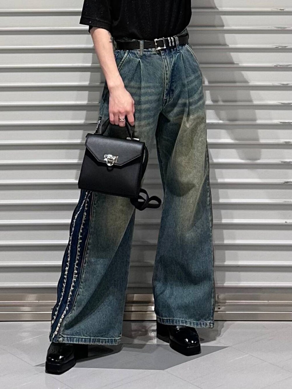 ブラック系のドレスシューズ、ブラック系のショルダーバッグ、ブルー系のデニムパンツを着用したメンズの春コーディネートの3枚目の写真