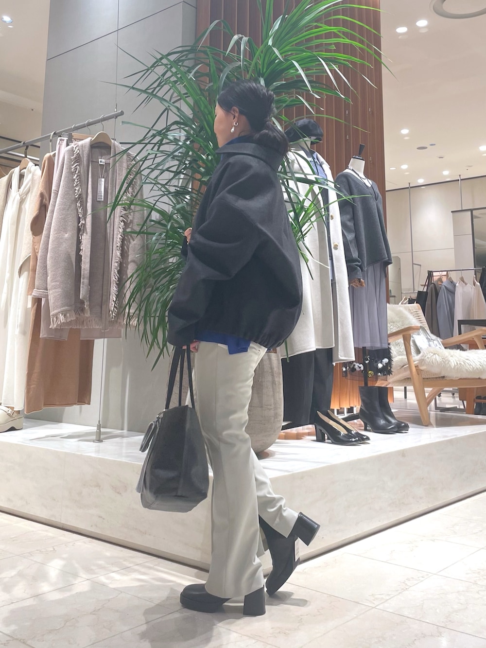 グレー系のその他アウター、ブルー系のニット/セーター、ブラック系のトートバッグを着用したレディースの秋コーディネートの4枚目の写真
