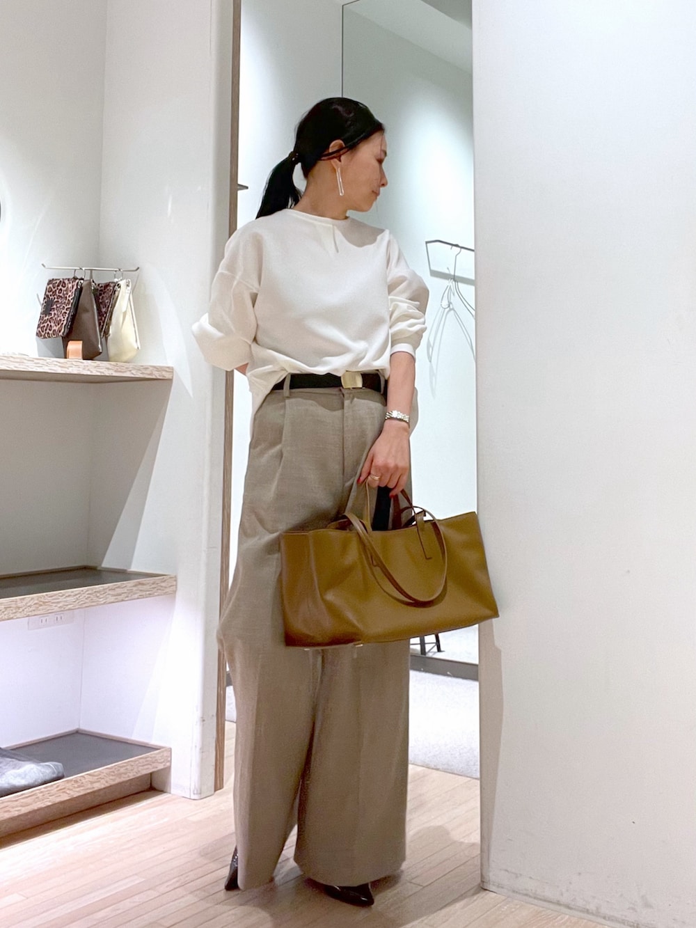 ブラウン系のトートバッグ、ブラウン系のパンプス、ホワイト系のシャツ/ブラウスを着用したレディースの春コーディネートの2枚目の写真