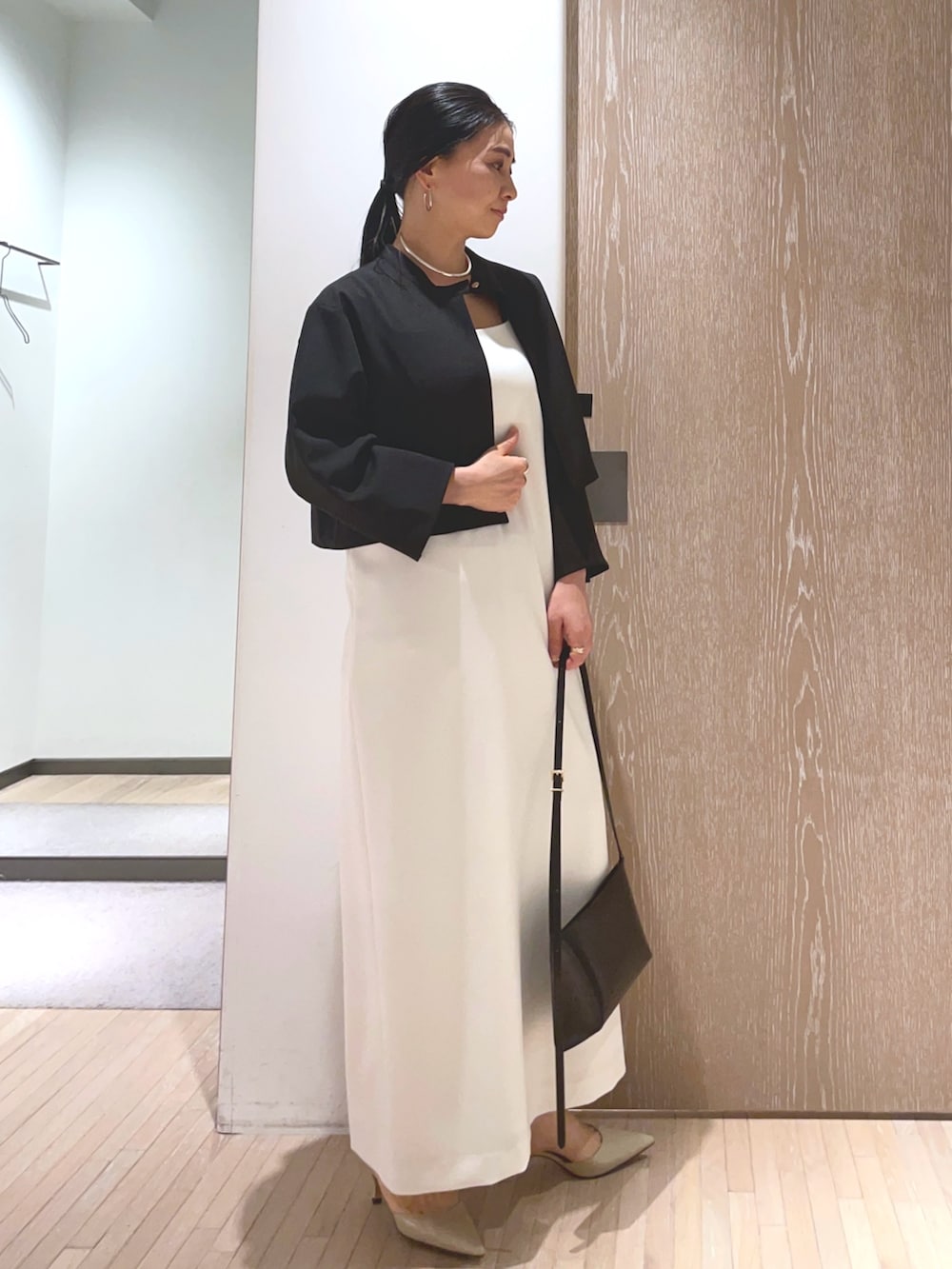 ブラック系のショルダーバッグ、ベージュ系のパンプス、ホワイト系のワンピースを着用したレディースの春コーディネートの4枚目の写真