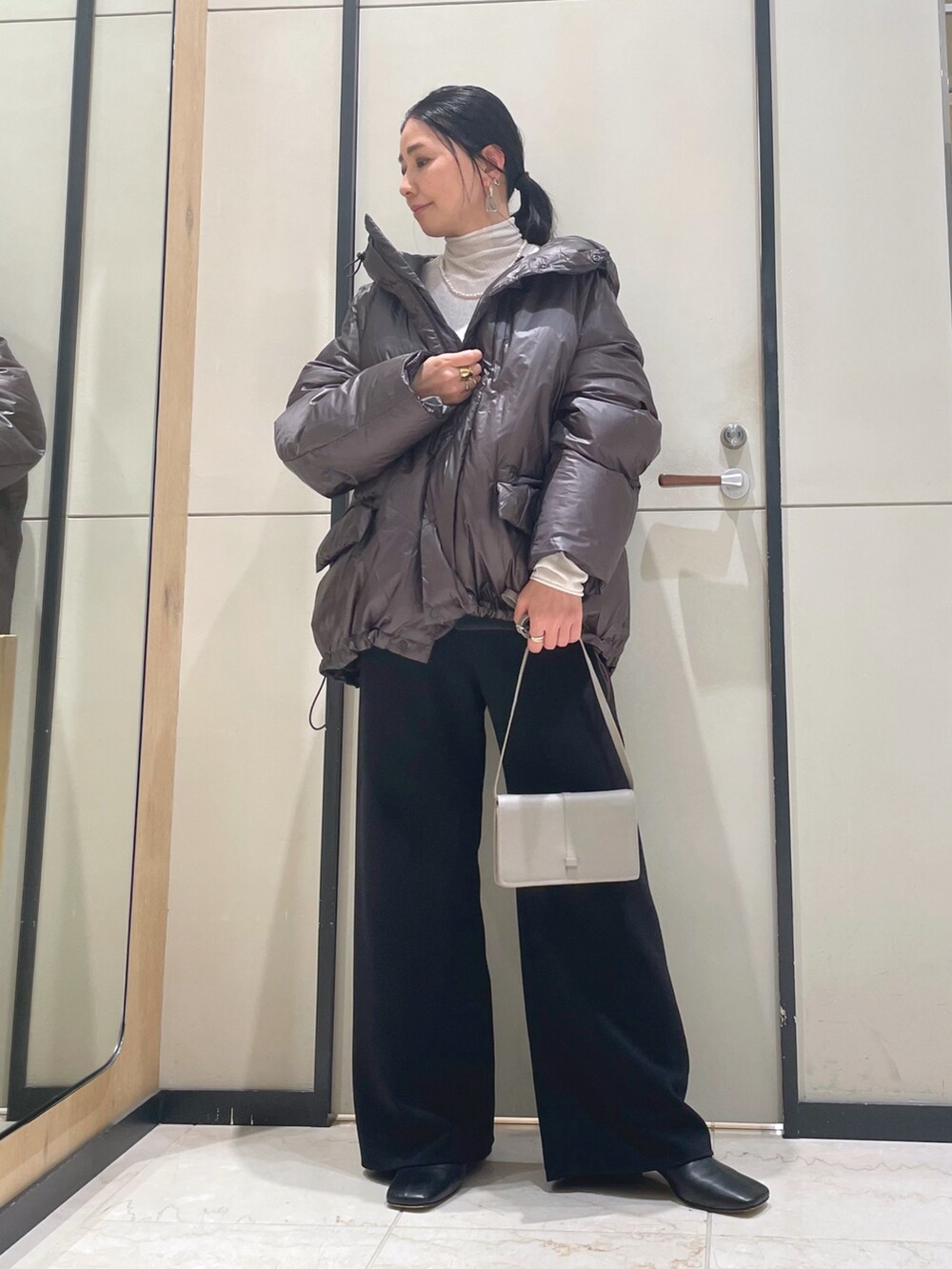 ブラック系のその他パンツ、ホワイト系のニット/セーター、ブラウン系のダウンジャケット/コートを着用したレディースの秋コーディネートの4枚目の写真