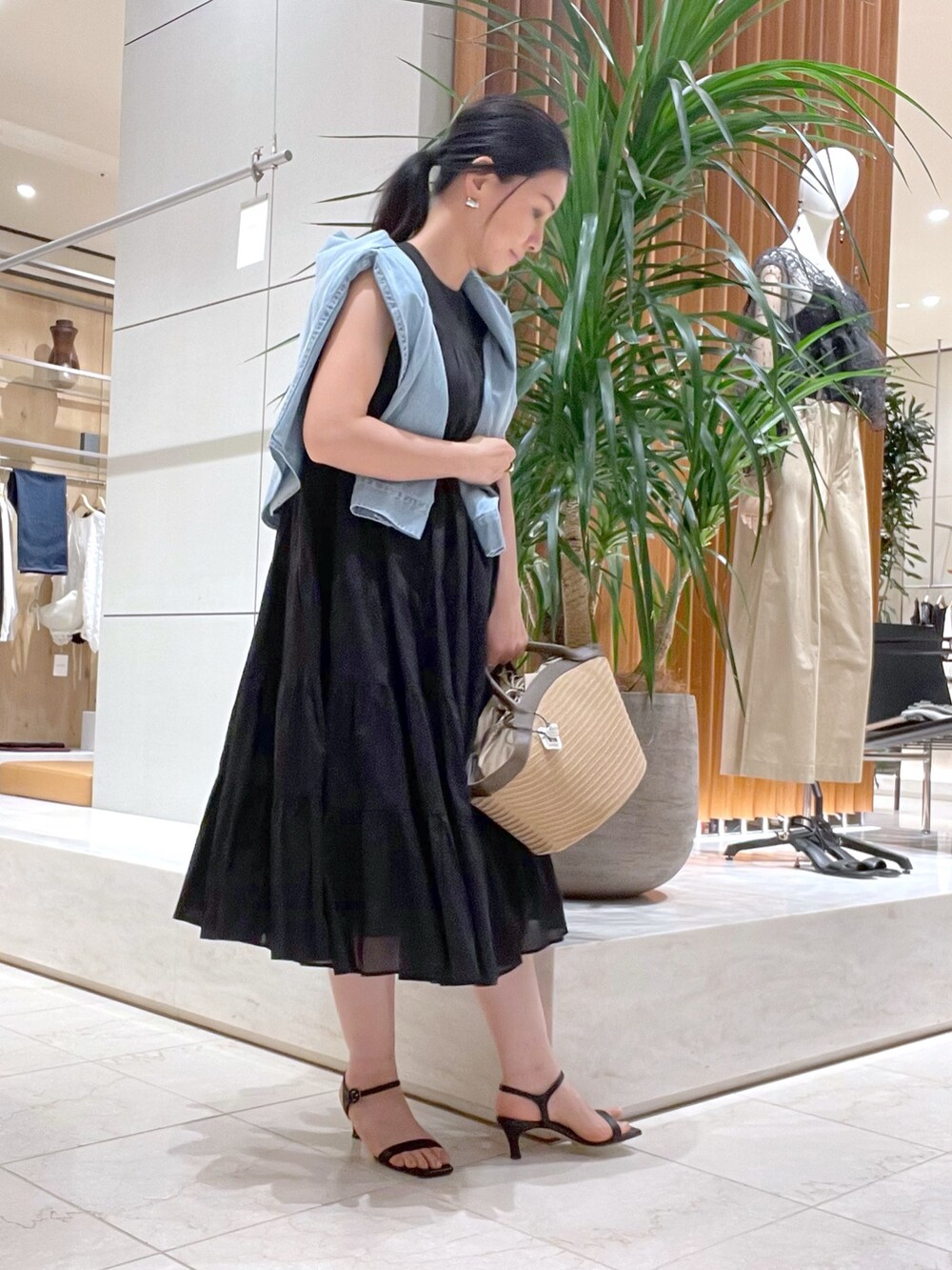 ブラック系のワンピース、ブラック系のサンダル、ブルー系のシャツ/ブラウスを着用したレディースの春コーディネートの4枚目の写真