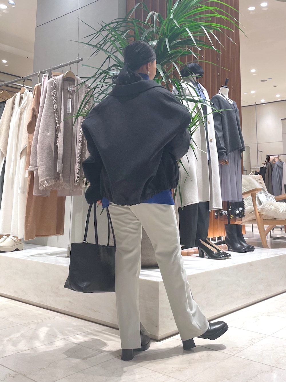 グレー系のその他アウター、ブルー系のニット/セーター、ブラック系のトートバッグを着用したレディースの秋コーディネートの3枚目の写真