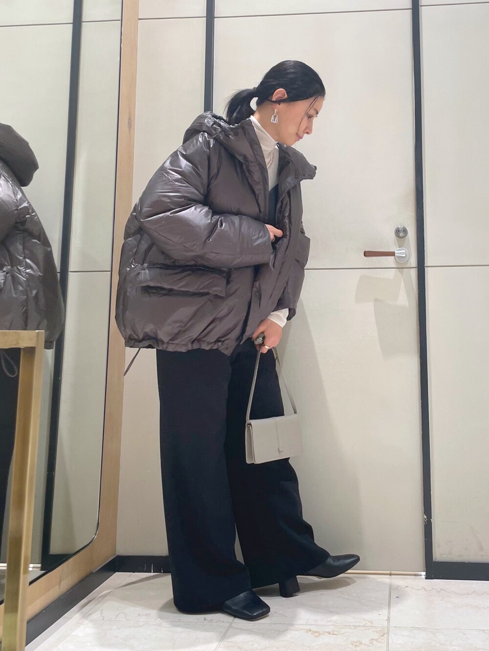 ブラック系のその他パンツ、ホワイト系のニット/セーター、ブラウン系のダウンジャケット/コートを着用したレディースの秋コーディネートの6枚目の写真