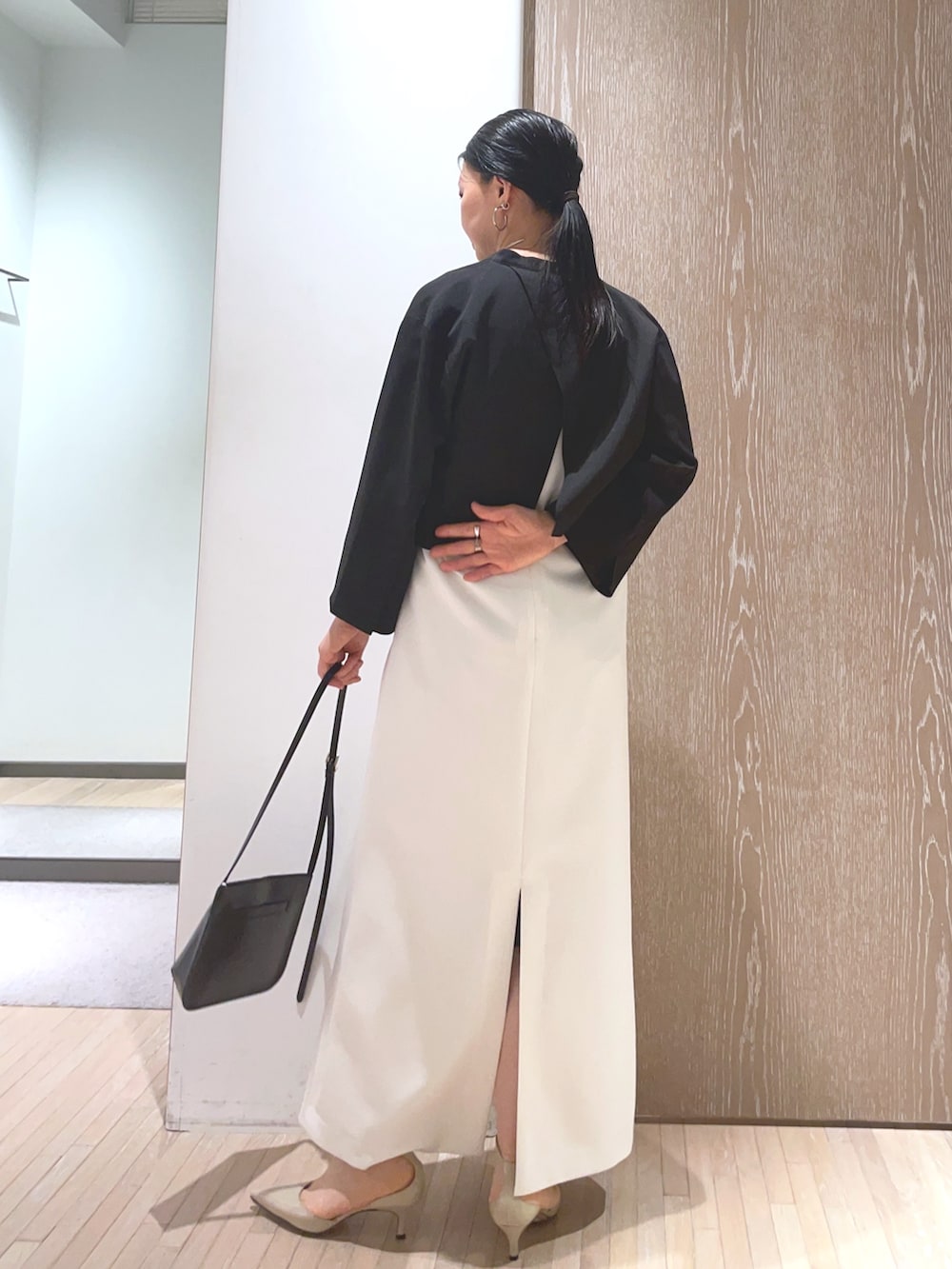 ブラック系のショルダーバッグ、ベージュ系のパンプス、ホワイト系のワンピースを着用したレディースの春コーディネートの3枚目の写真