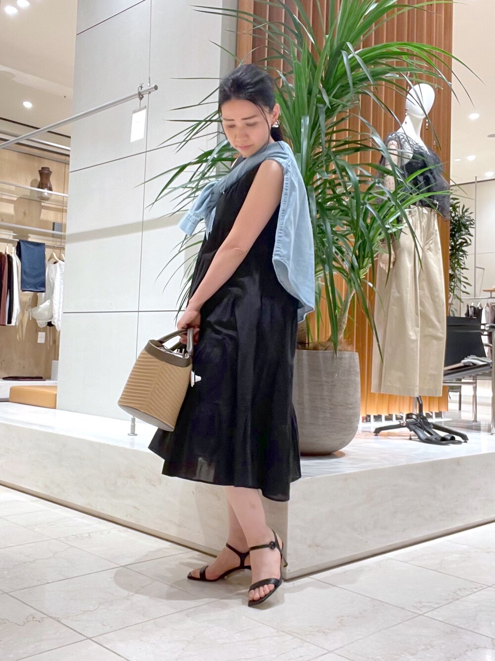 ブラック系のワンピース、ブラック系のサンダル、ブルー系のシャツ/ブラウスを着用したレディースの春コーディネートの5枚目の写真