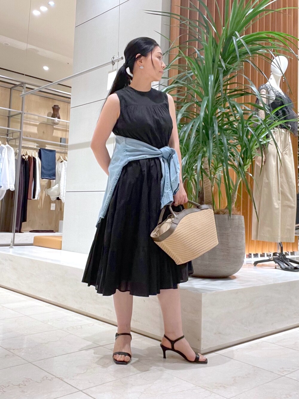 ブラック系のワンピース、ブラック系のサンダル、ブルー系のシャツ/ブラウスを着用したレディースの春コーディネートの3枚目の写真