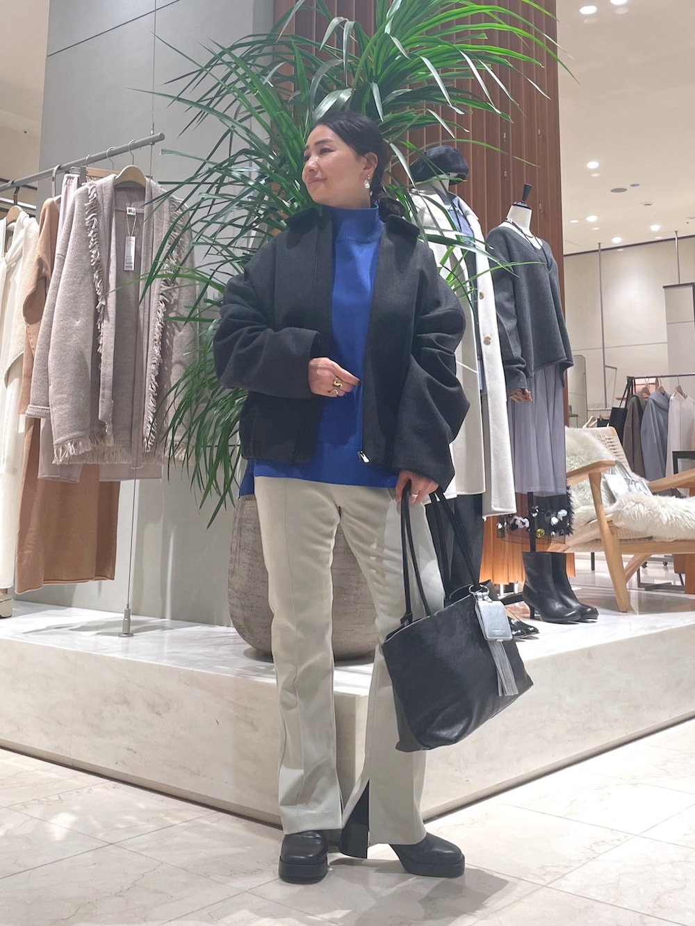 グレー系のその他アウター、ブルー系のニット/セーター、ブラック系のトートバッグを着用したレディースの秋コーディネートの2枚目の写真