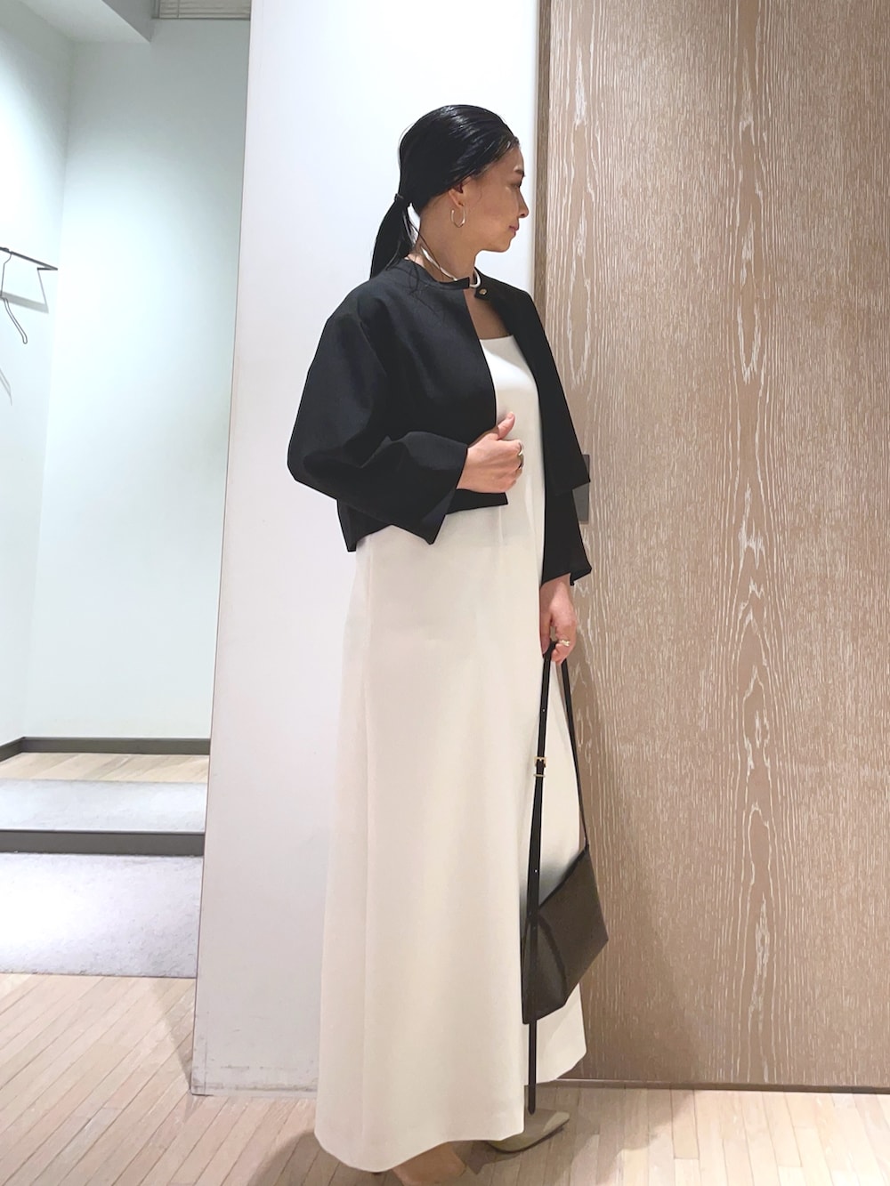 ブラック系のショルダーバッグ、ベージュ系のパンプス、ホワイト系のワンピースを着用したレディースの春コーディネートの2枚目の写真