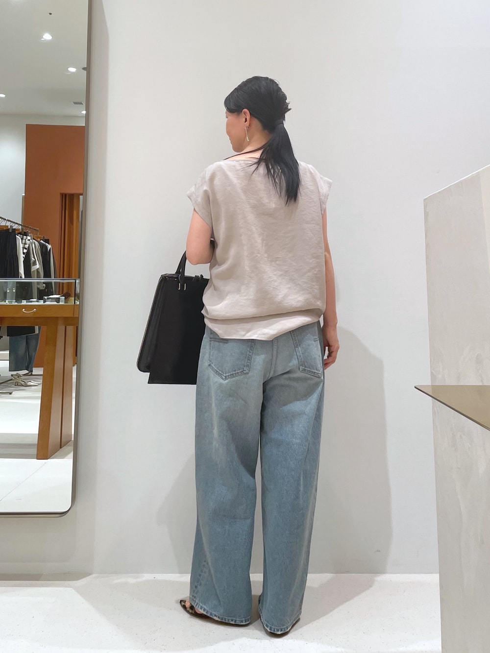 イエロー系のサンダル、ベージュ系のシャツ/ブラウス、ブルー系のデニムパンツを着用したレディースの夏コーディネートの3枚目の写真