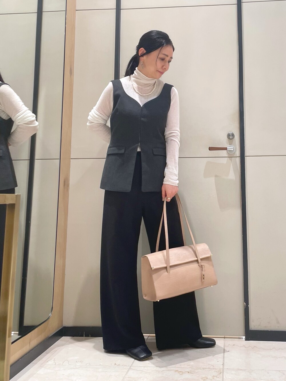 ブラック系のその他パンツ、ホワイト系のニット/セーター、ブラウン系のダウンジャケット/コートを着用したレディースの秋コーディネートの9枚目の写真