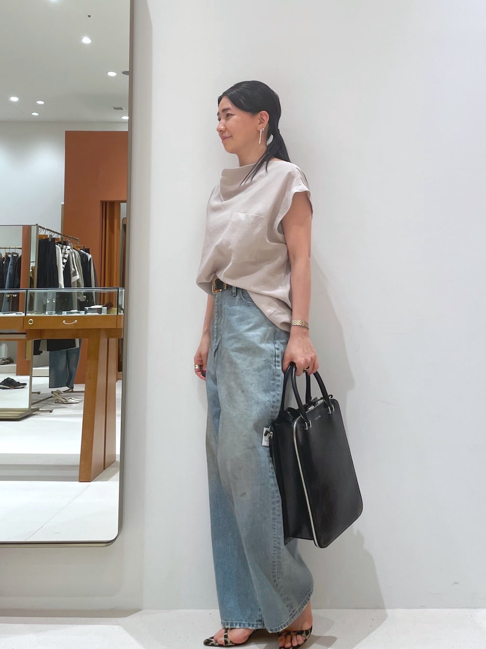 イエロー系のサンダル、ベージュ系のシャツ/ブラウス、ブルー系のデニムパンツを着用したレディースの夏コーディネートの2枚目の写真