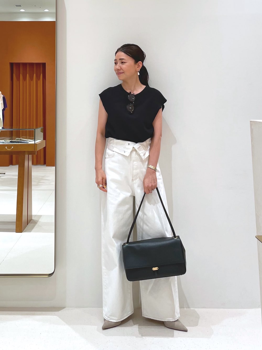 ブラック系のシャツ/ブラウス、グレー系のパンプス、ホワイト系のデニムパンツを着用したレディースの夏コーディネートの5枚目の写真