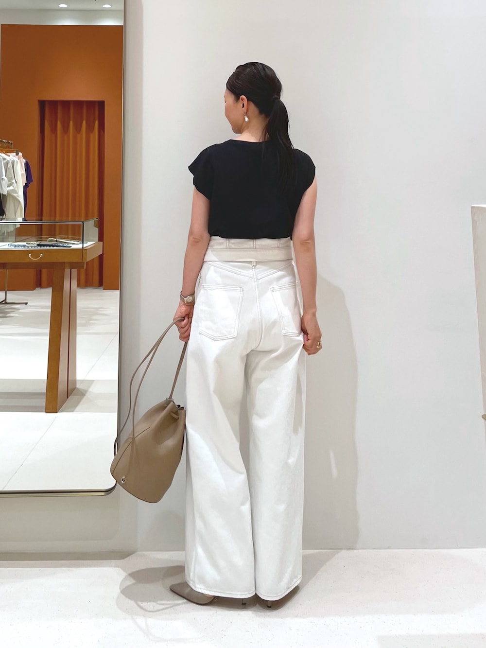 ブラック系のシャツ/ブラウス、グレー系のパンプス、ホワイト系のデニムパンツを着用したレディースの夏コーディネートの2枚目の写真