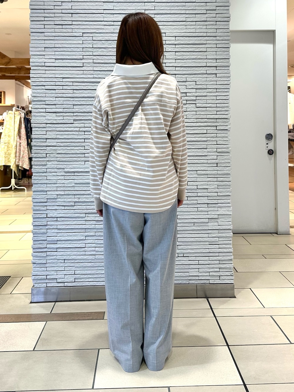 ベージュ系のトップス、ベージュ系のバッグ、グレー系のパンツを着用したレディースの冬コーディネートの3枚目の写真