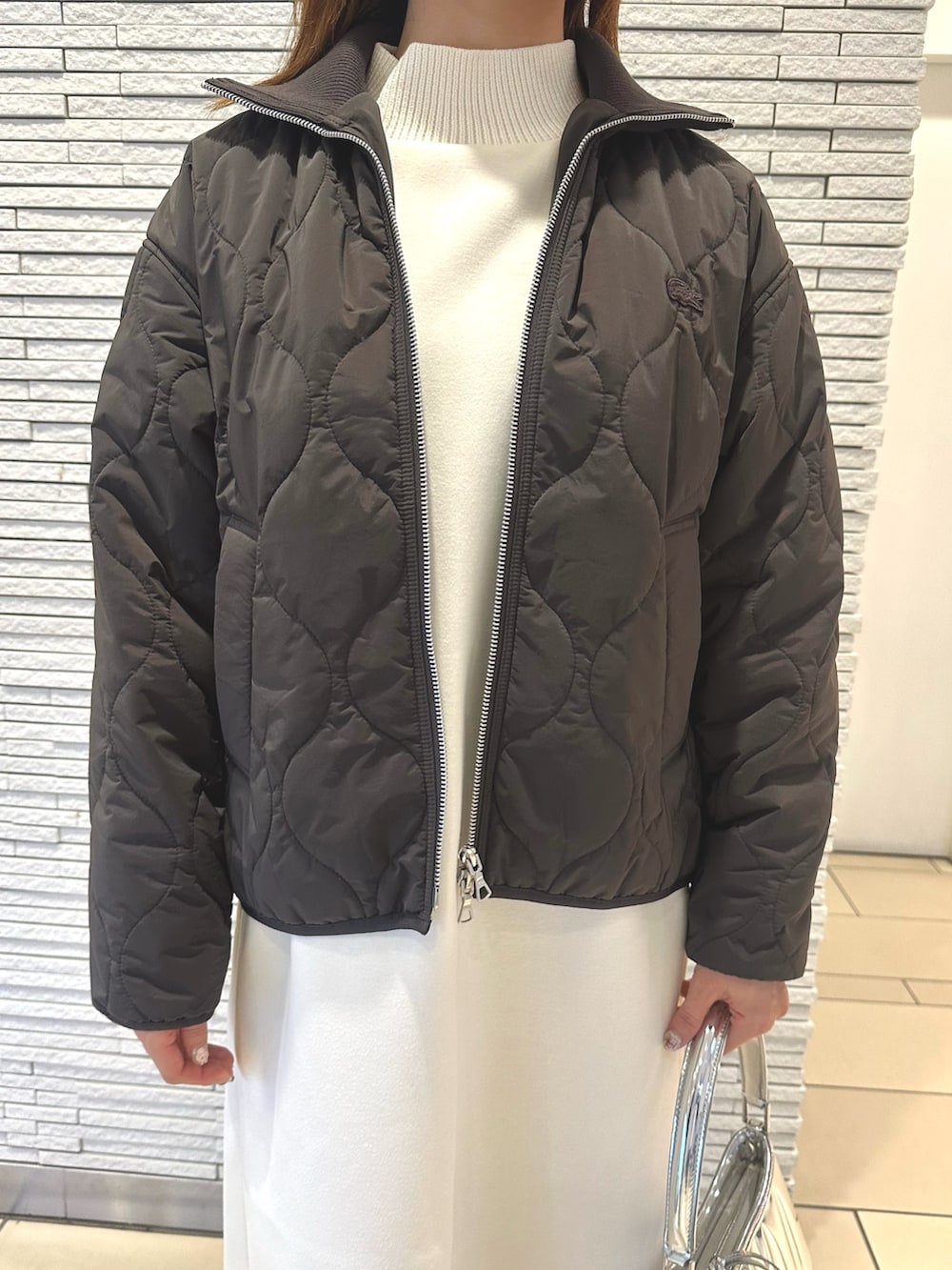 ブラウン系のダウンジャケット/コート、ホワイト系のワンピース、シルバー系のショルダーバッグを着用したレディースの秋コーディネートの3枚目の写真