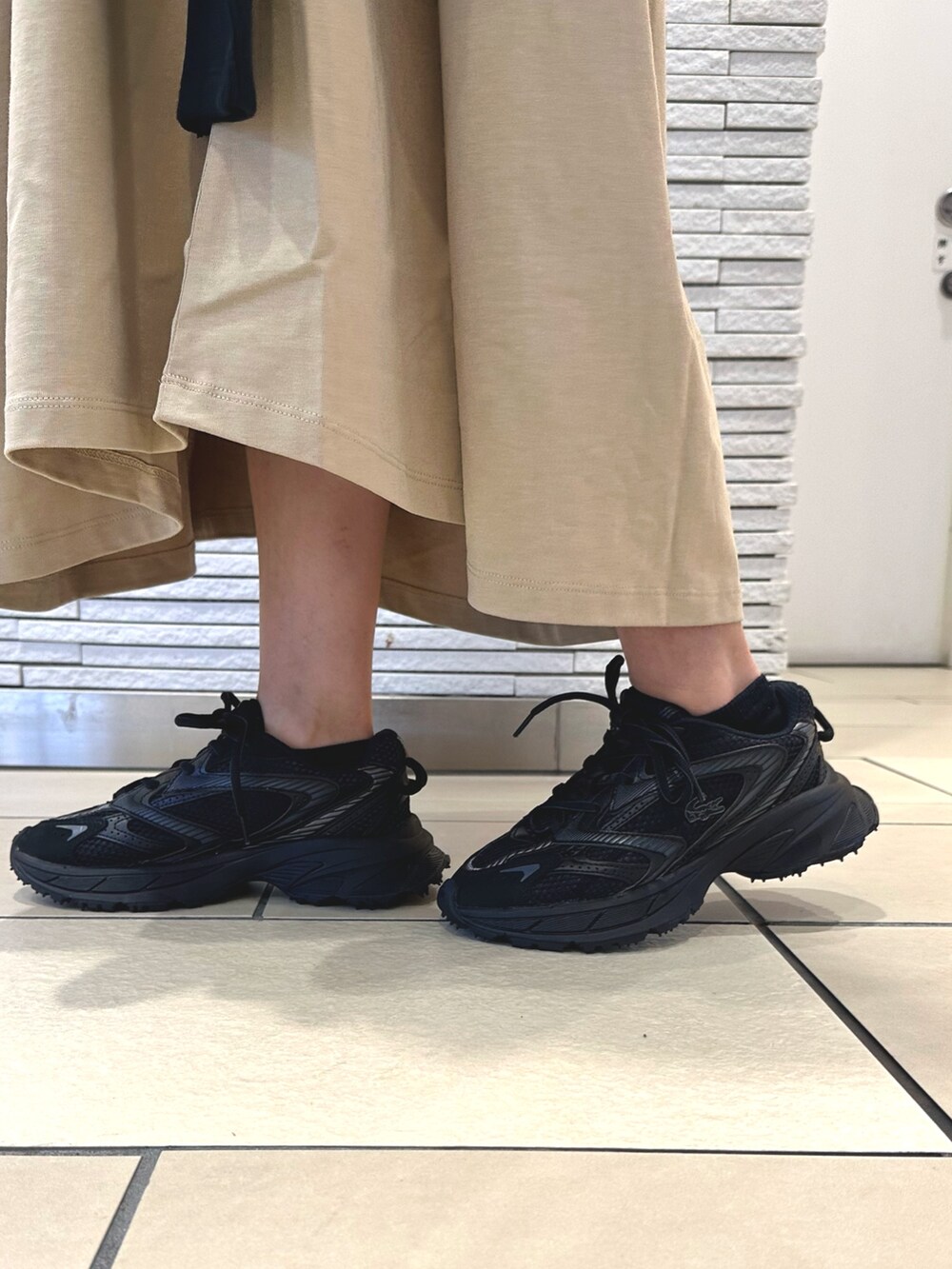 ベージュ系のワンピース、ブラック系のカーディガン/ボレロ、ブラック系のショルダーバッグを着用したレディースの夏コーディネートの6枚目の写真