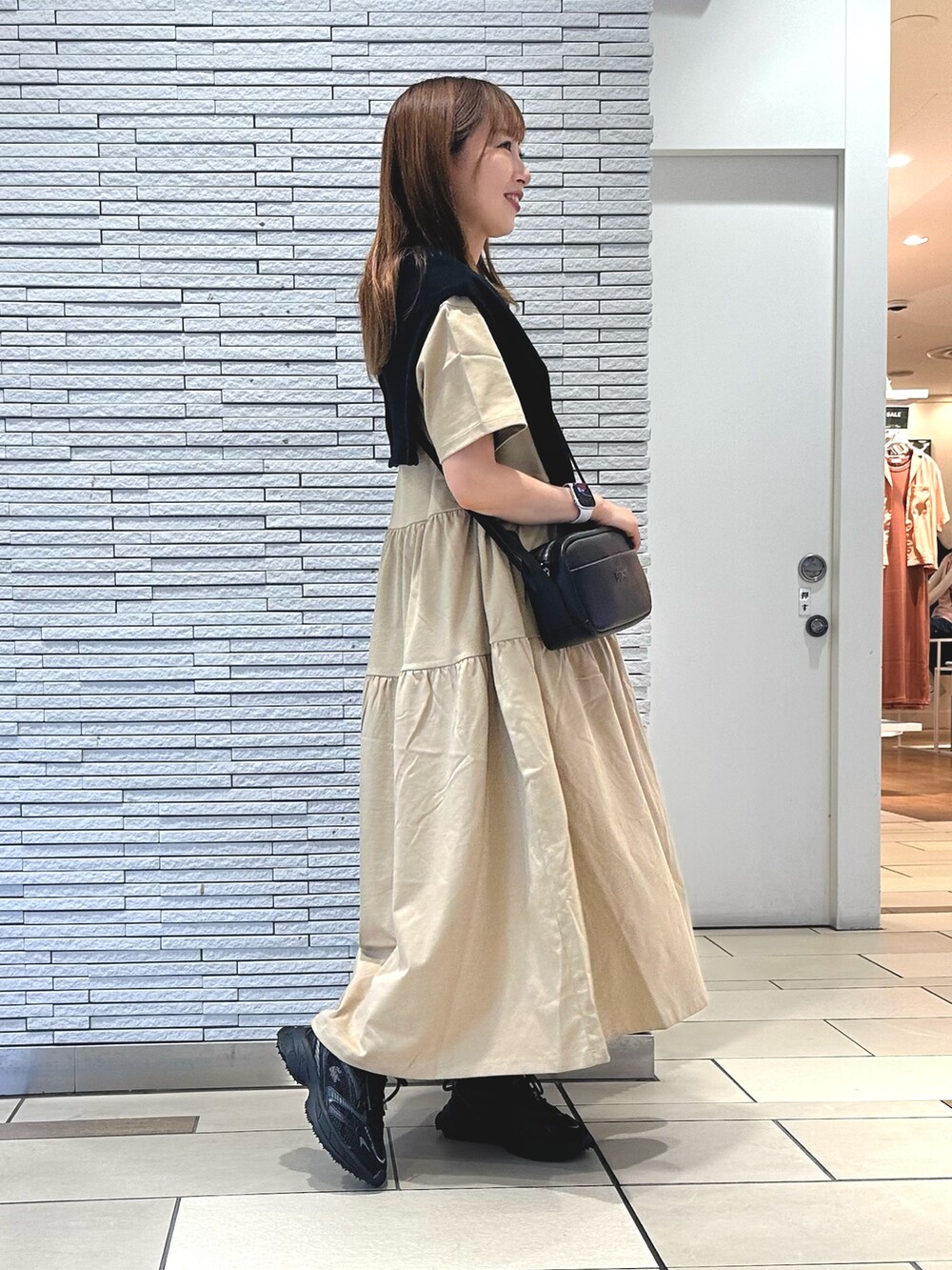 ベージュ系のワンピース、ブラック系のカーディガン/ボレロ、ブラック系のショルダーバッグを着用したレディースの夏コーディネートの2枚目の写真