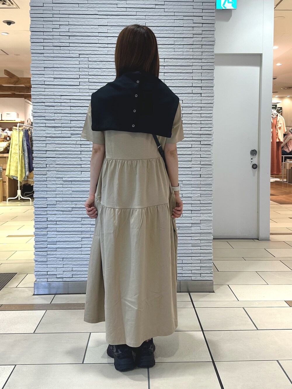 ベージュ系のワンピース、ブラック系のカーディガン/ボレロ、ブラック系のショルダーバッグを着用したレディースの夏コーディネートの3枚目の写真