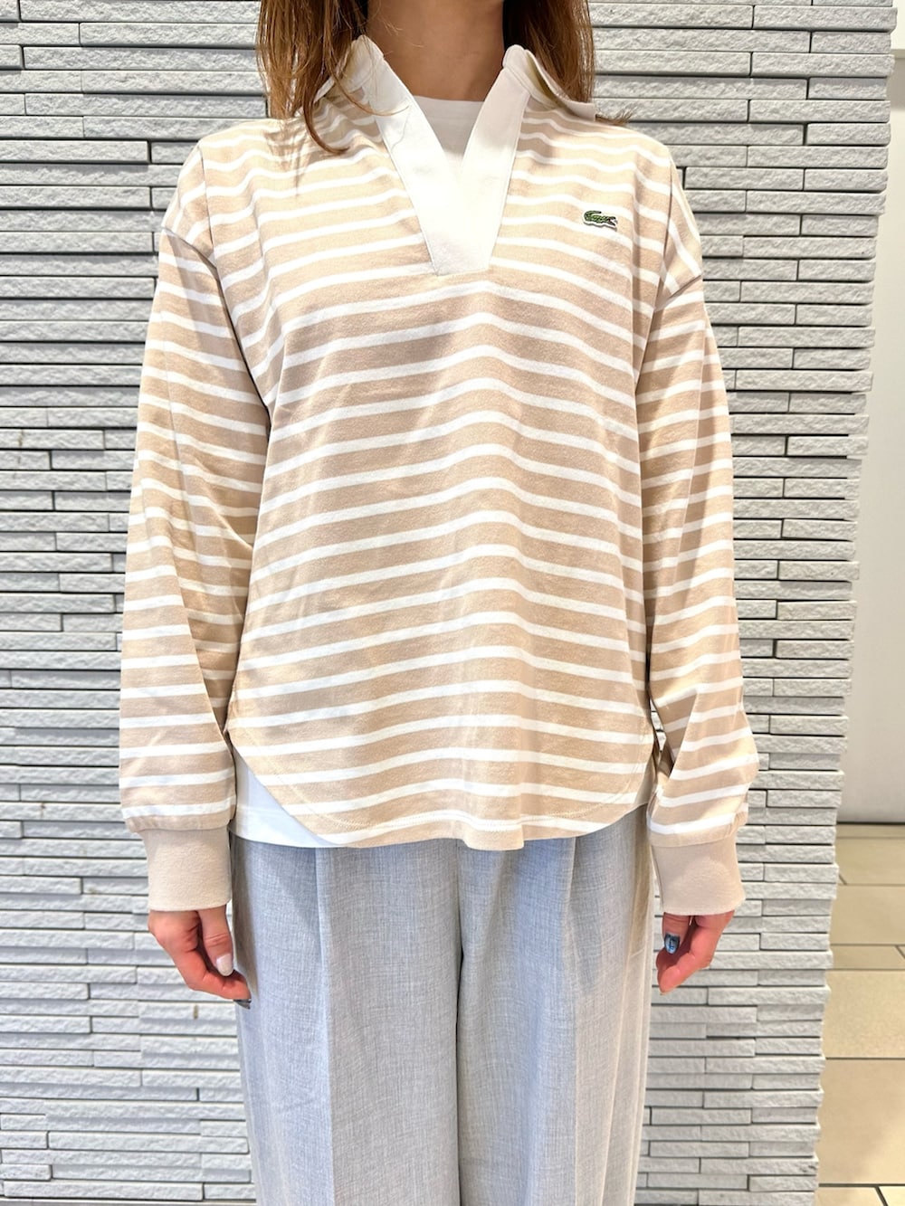 ベージュ系のトップス、ベージュ系のバッグ、グレー系のパンツを着用したレディースの冬コーディネートの2枚目の写真