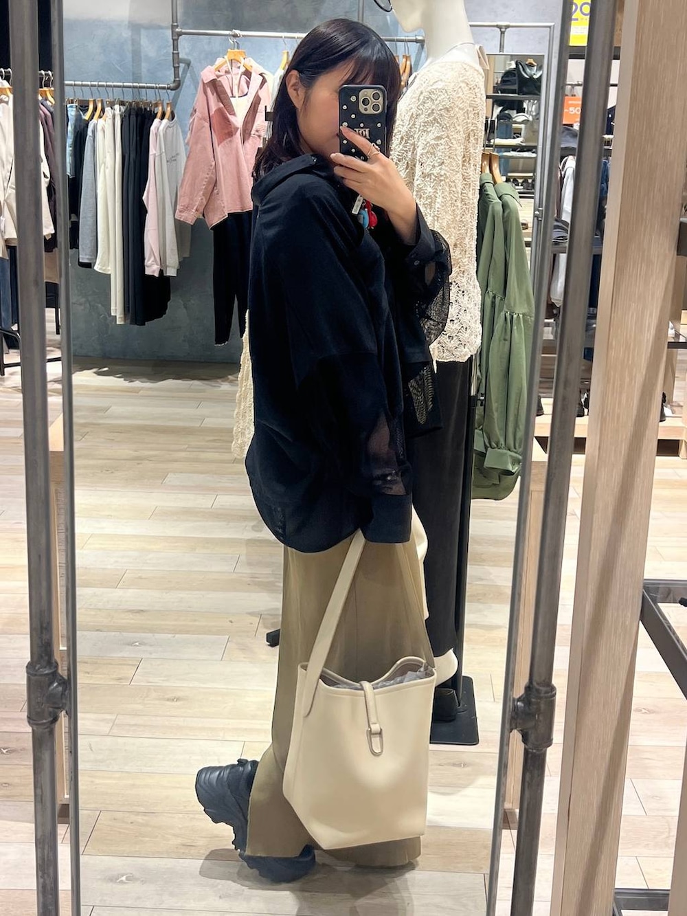 グリーン系のスカート、ホワイト系のトートバッグ、ブラック系のシャツ/ブラウスを着用したレディースの春コーディネートの2枚目の写真