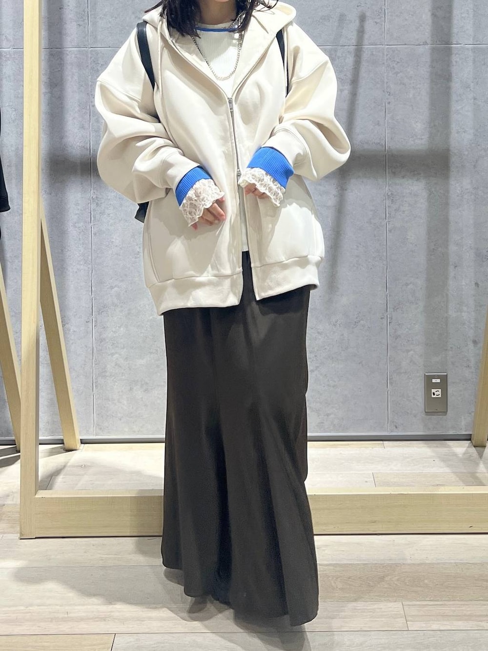 ホワイト系のパーカー、ブラック系のショルダーバッグ、ブラウン系のスカートを着用したレディースの春コーディネートの2枚目の写真