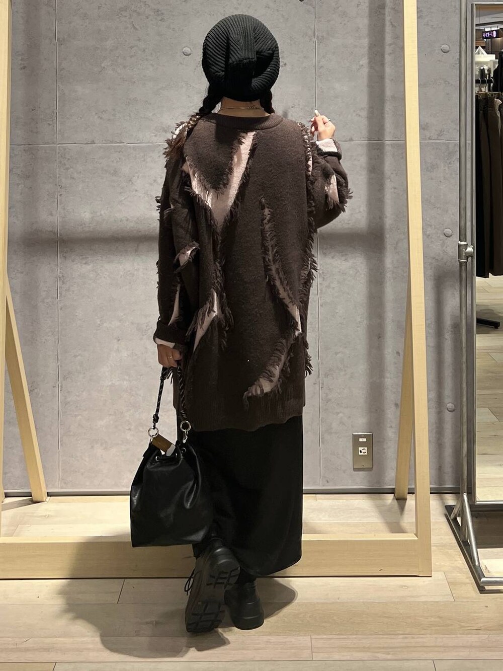 ブラック系のショルダーバッグ、ブラック系のスカート、ブラウン系のニット/セーターを着用したレディースの冬コーディネートの3枚目の写真