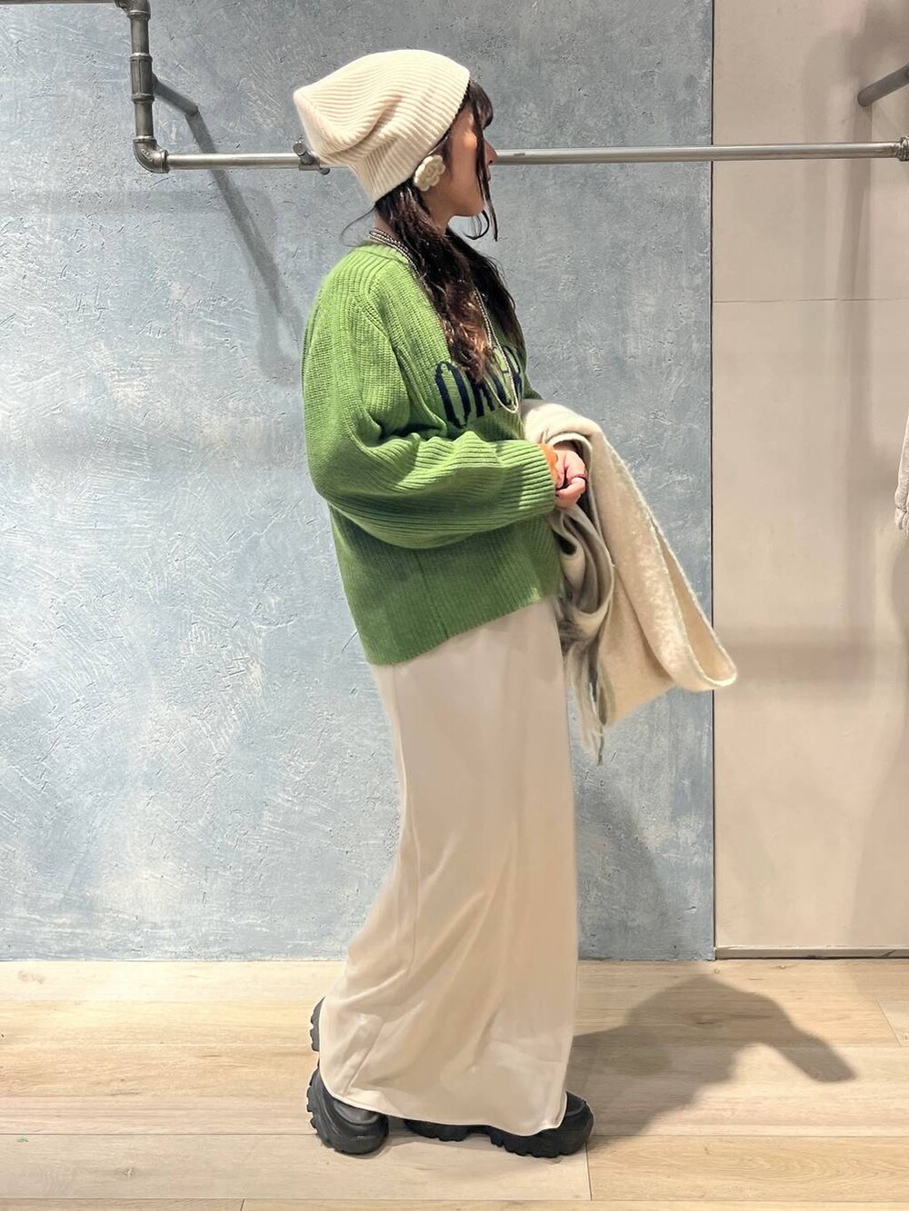 ブラック系のTシャツ/カットソー、ホワイト系のスカート、グリーン系のニット/セーターを着用したレディースの冬コーディネートの4枚目の写真